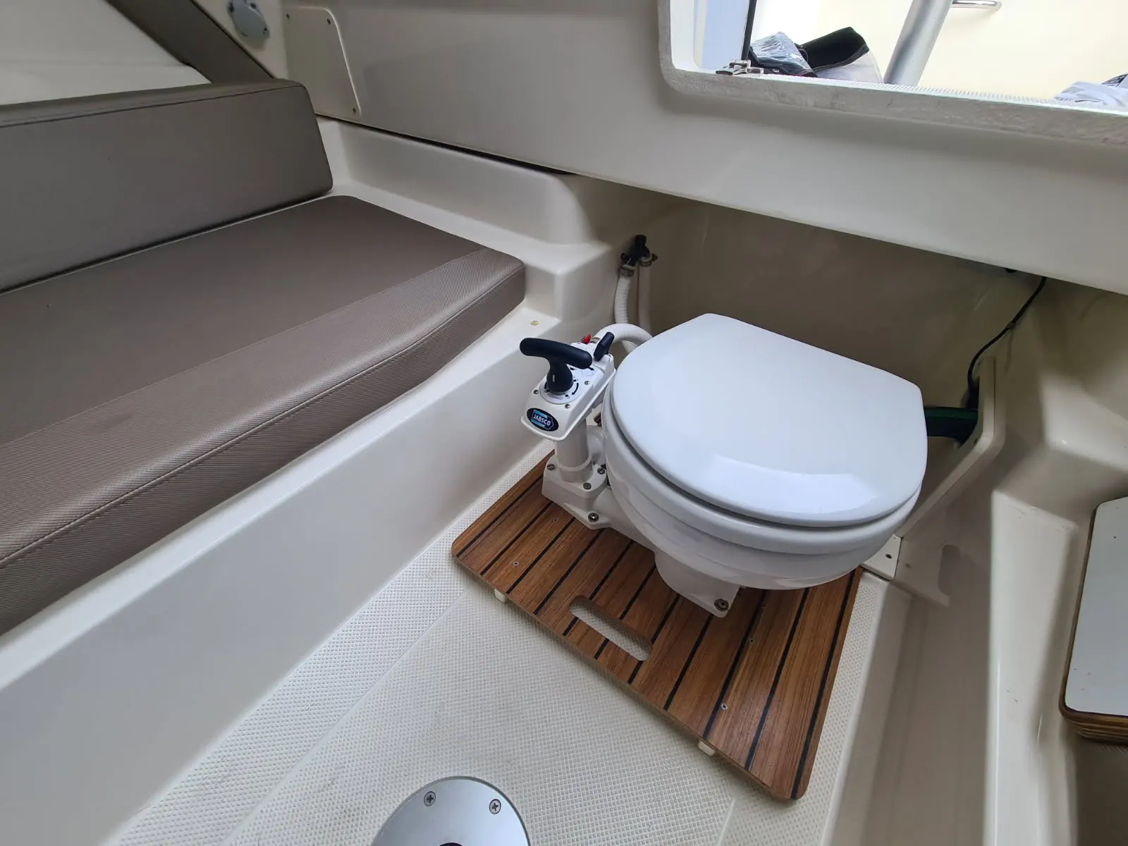 Quicksilver 750 Week-End — Vue intérieure des toilettes marines avec banquette et plancher en teck.