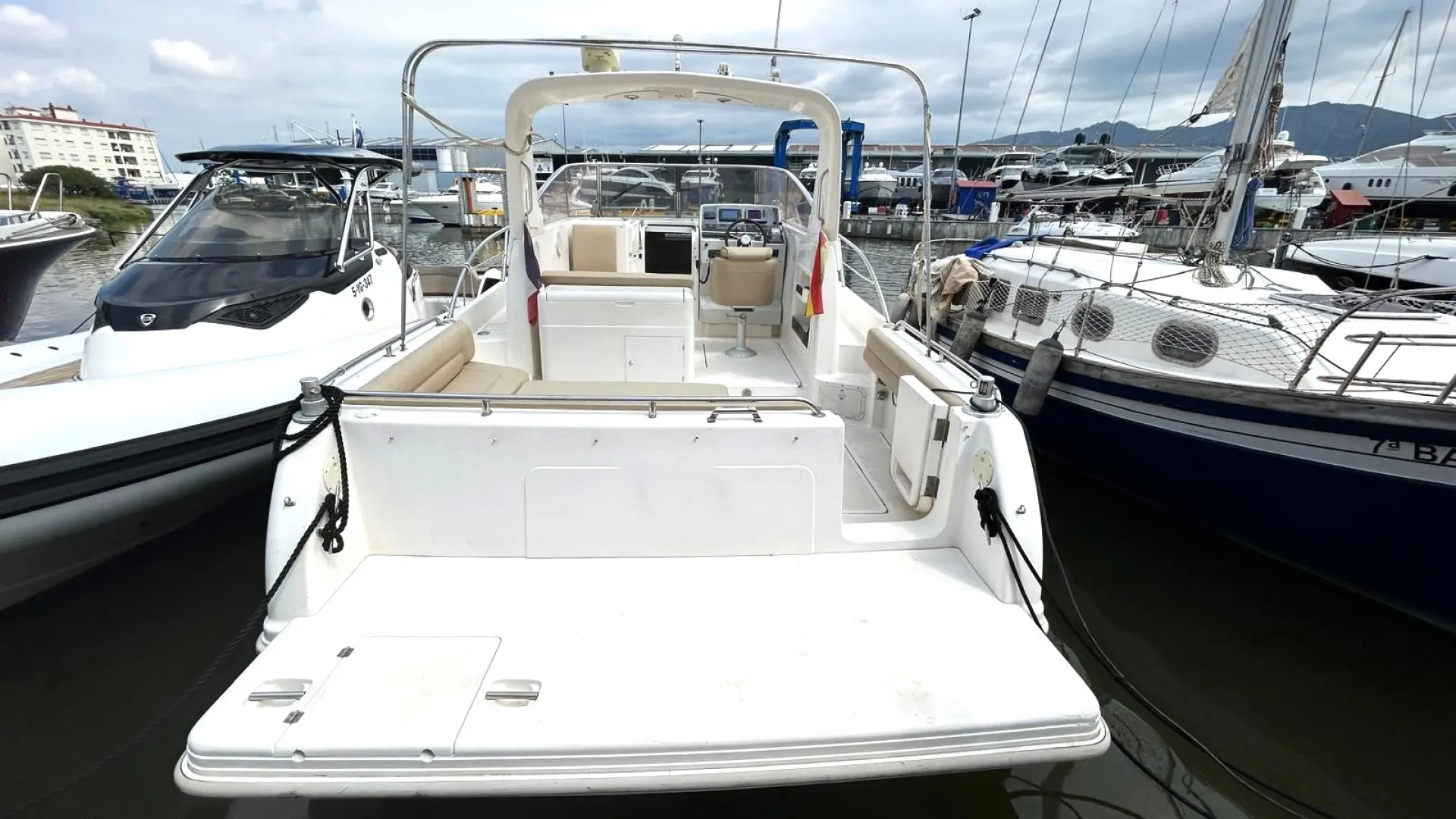 Faeton 980 Sport — Vue arrière d’un bateau à moteur amarré dans une marina, cockpit et plateforme visibles.