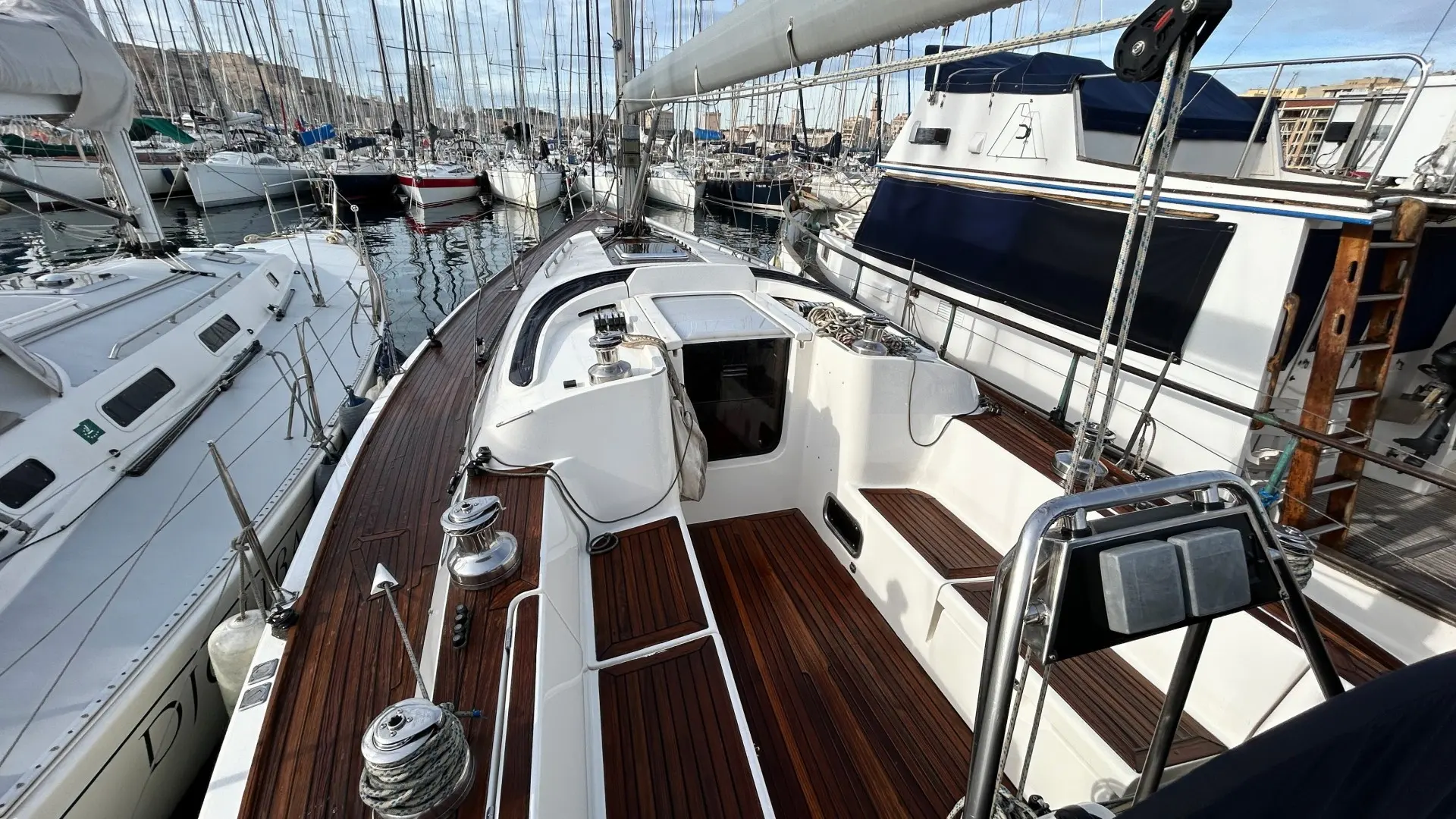 X-Yachts X-40 — Vue du cockpit et du pont en teck d’un voilier amarré dans une marina.