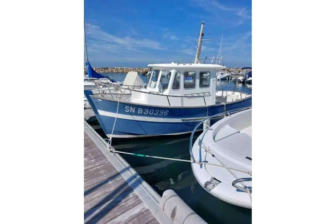 Rhea 650 — Bateau à cabine bleu et blanc amarré dans un port de plaisance.