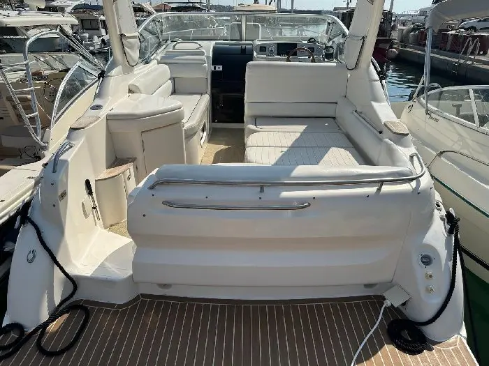 Sealine Bolero 28 — Cockpit arrière d’un bateau blanc avec banquettes, poste de pilotage et plage de bain.