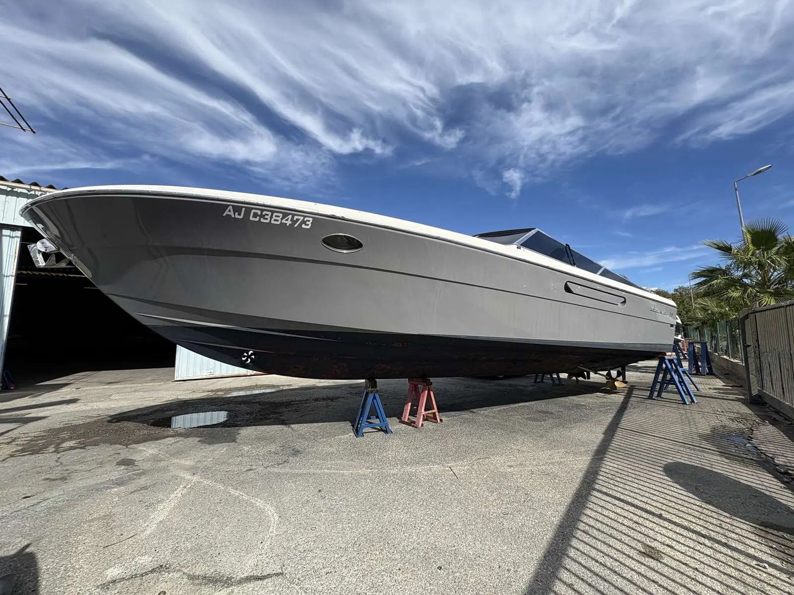 Itama 38 — Bateau à moteur gris photographié à terre dans une cour de maintenance.