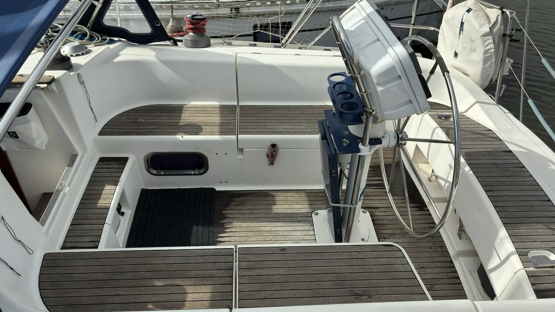 Dufour 43 — Vue du cockpit arrière d’un voilier, avec barre à roue et bancs en teck.