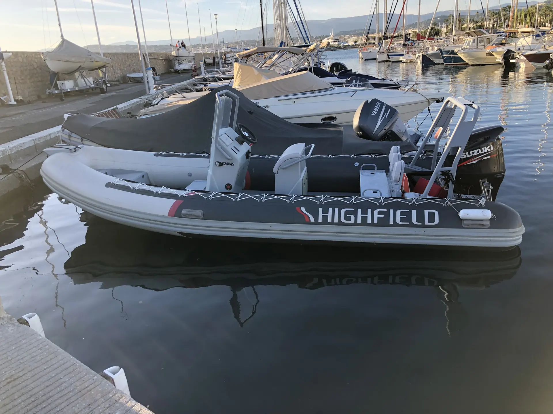 Highfield OM 590 — Bateau semi-rigide amarré dans un port, vu de profil avec son moteur hors-bord.