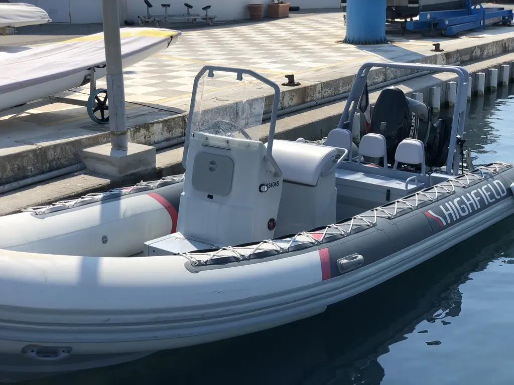 Highfield OM 590 — Bateau semi-rigide amarré, vu de trois quarts, avec console centrale et moteur hors-bord.