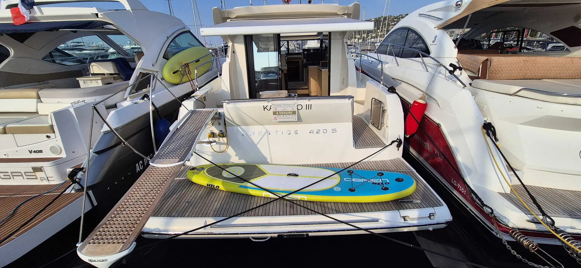 Prestige Yachts 420 S — Vue arrière d’un bateau à moteur amarré, avec plateforme et planche gonflable.