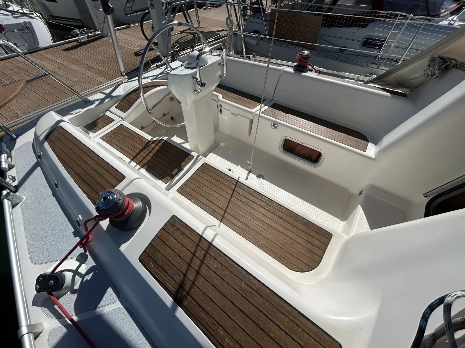Etap 37 S — Vue du cockpit d’un voilier avec barre à roue et pont en teck.