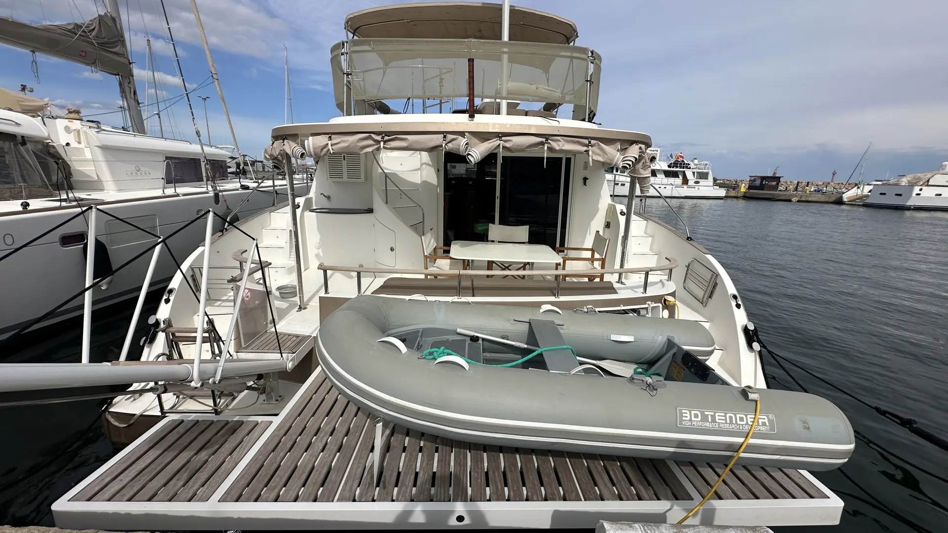 Fountaine Pajot Cumberland 44 — Vue arrière d’un bateau amarré, avec une annexe sur la plateforme.