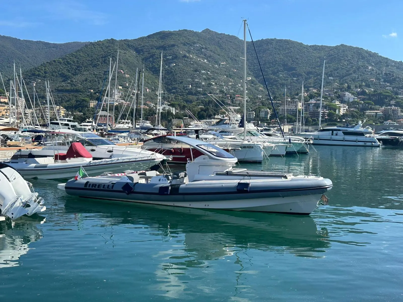 Pirelli Pzero 1100 Open — Bateau pneumatique Pirelli amarré dans une marina entourée de collines.