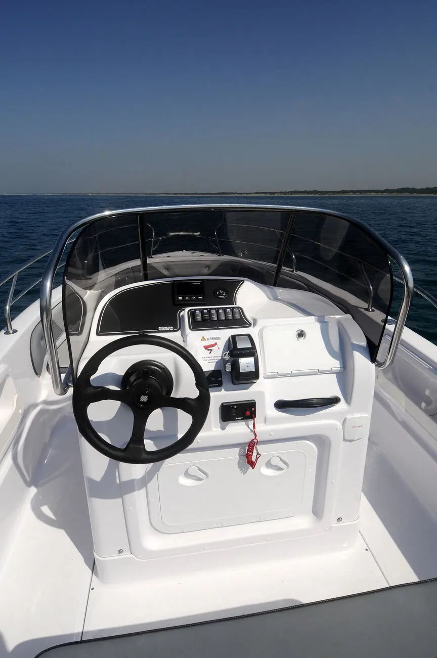 4XC H22CC — Vue du poste de pilotage avec volant, commandes et pare-brise sur l’eau.