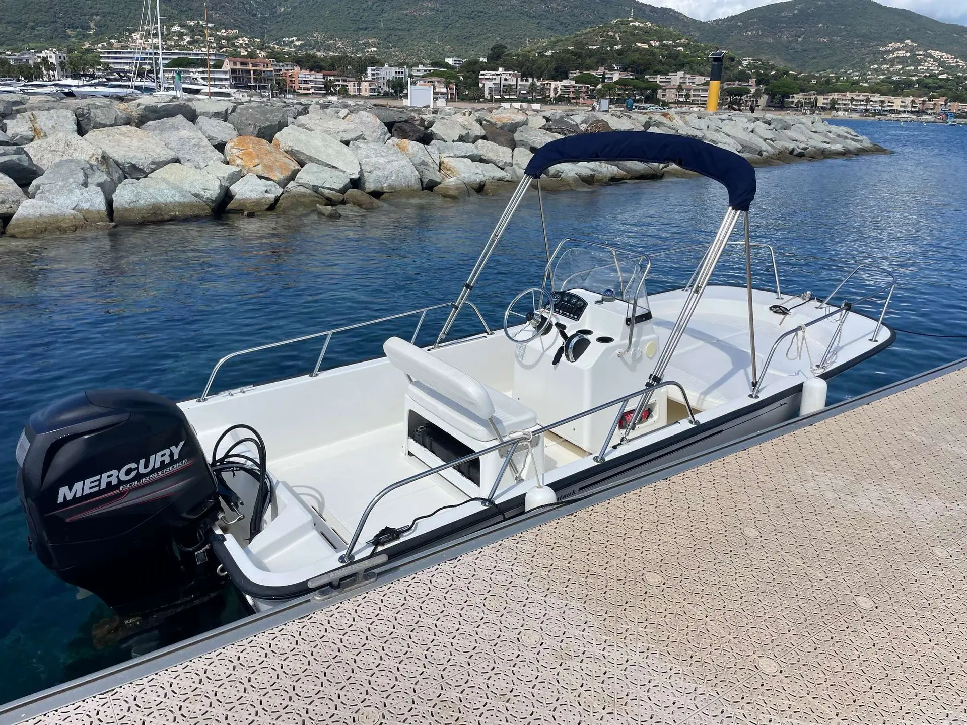 Boston Whaler 170 Montauk — Bateau à console centrale amarré au quai, vu de trois quarts arrière.