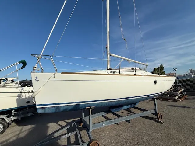 Beneteau First 211 — Voilier blanc vu de trois quarts, posé sur une remorque à terre.