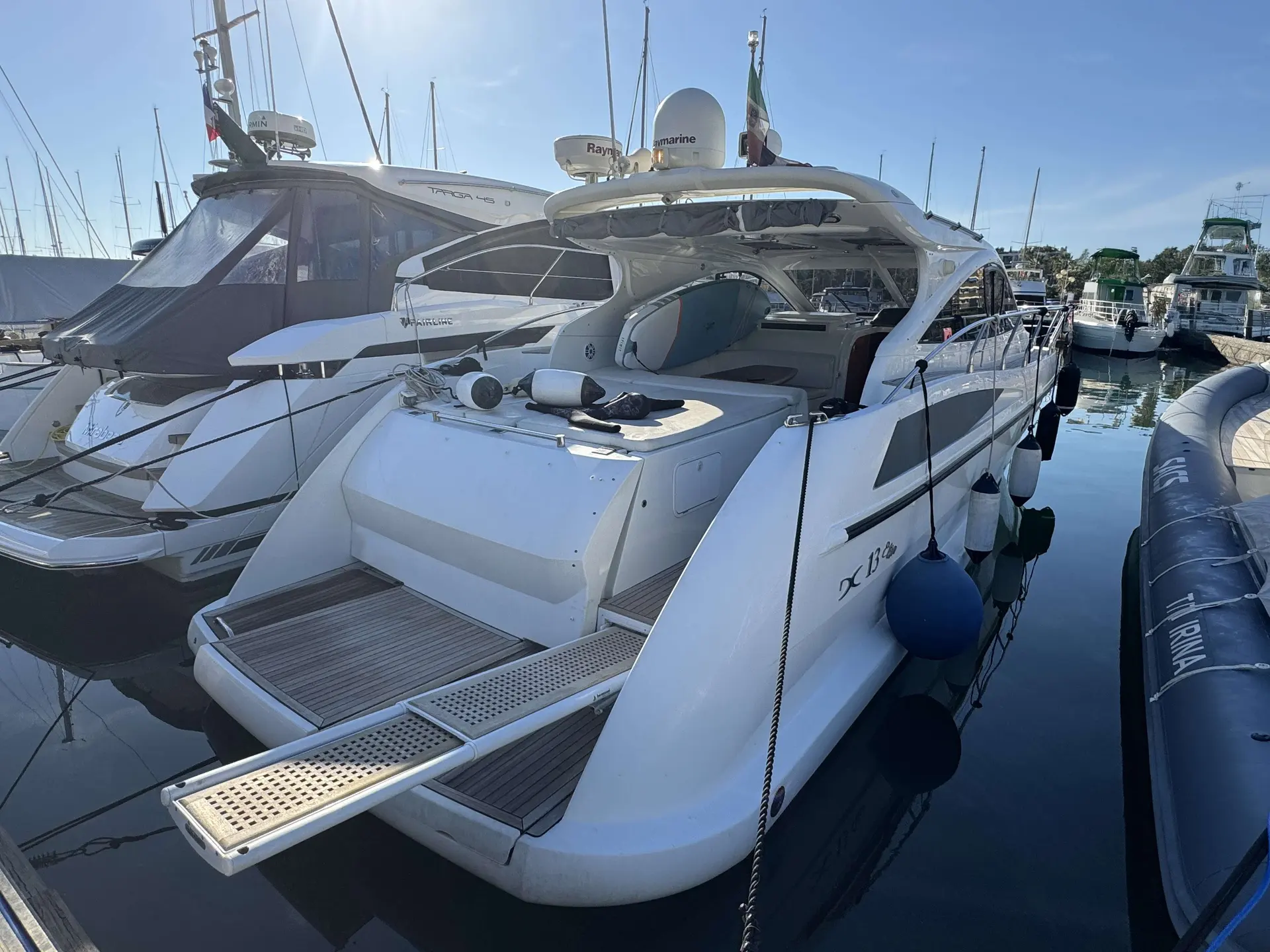 Della Pasqua DC 13 — Bateau blanc amarré, vu de trois quarts arrière dans une marina.