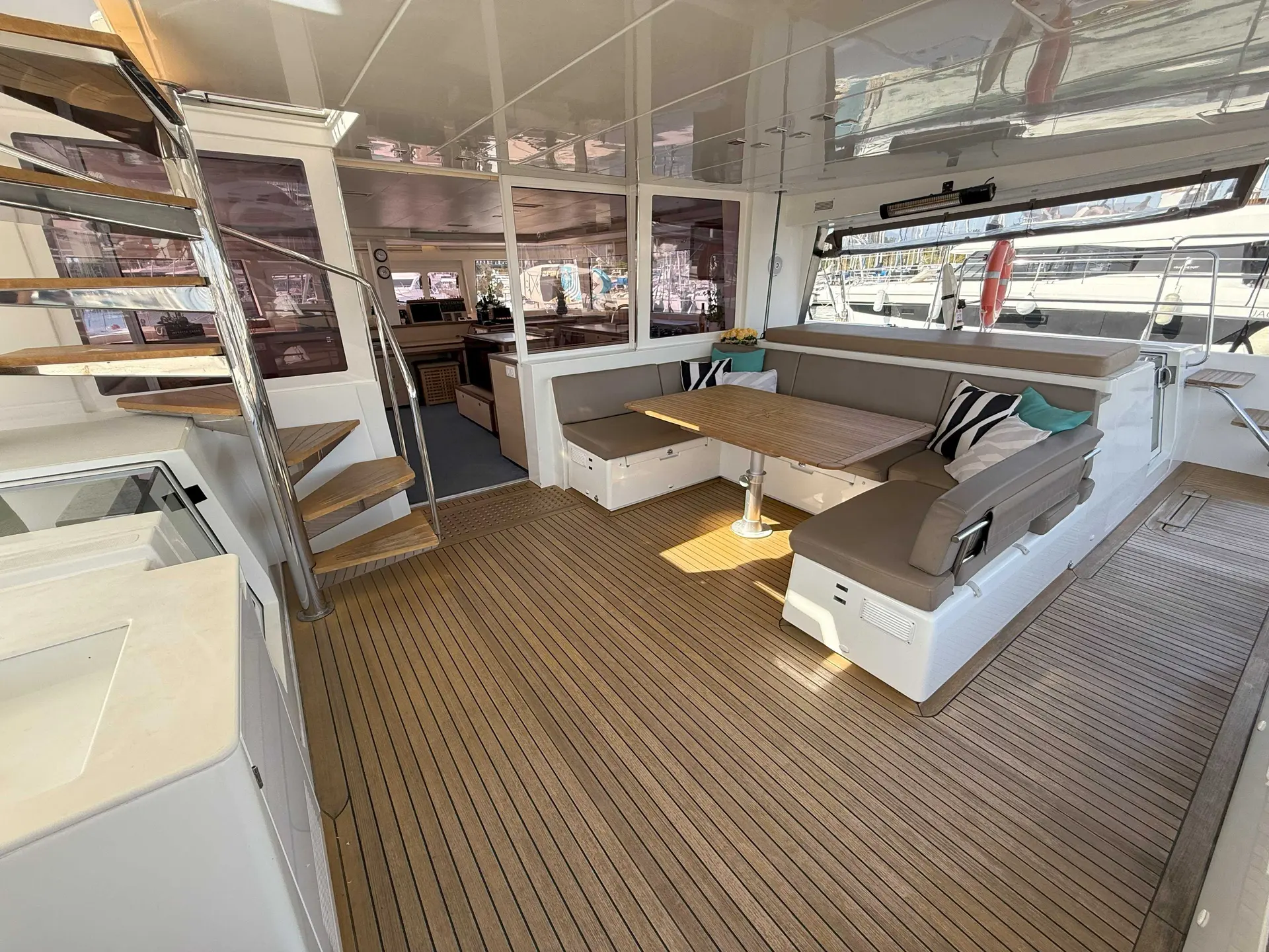 Lagoon 560 — Cockpit couvert avec salon, table, banquettes et accès à la cabine de pilotage.