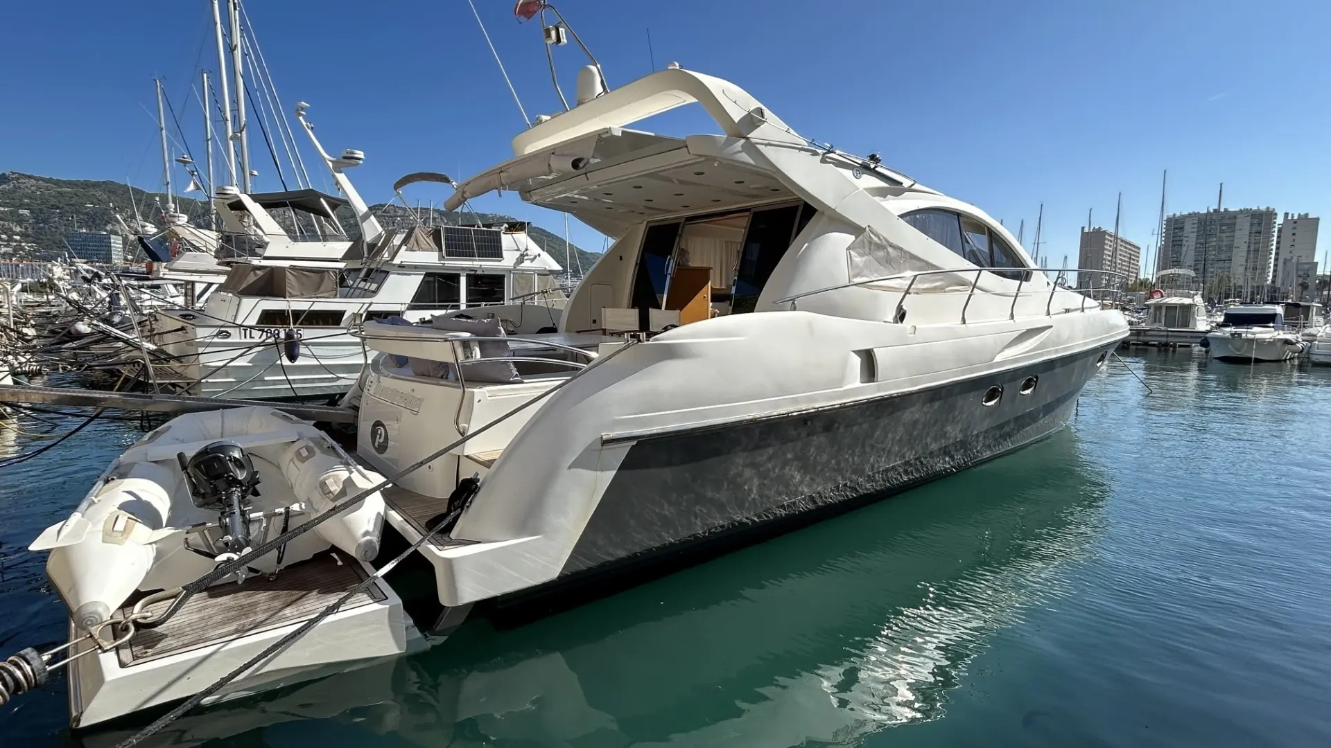 Innovazioni E Progetti Alena 54 — Vedette blanche amarrée, vue de trois quarts arrière dans un port.