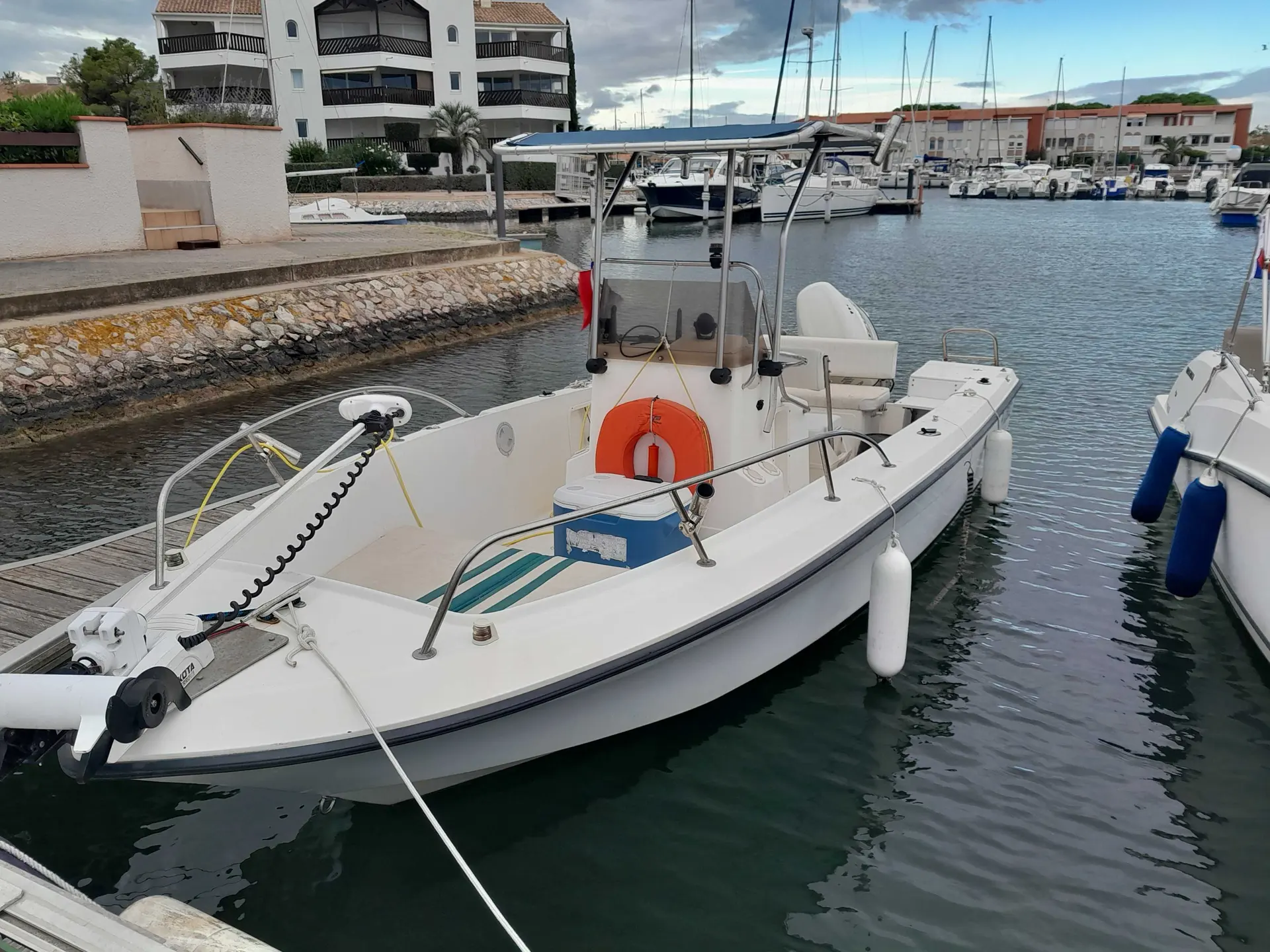Sunfisher 200 — Bateau à console centrale amarré dans une marina, vu de trois quarts avant.