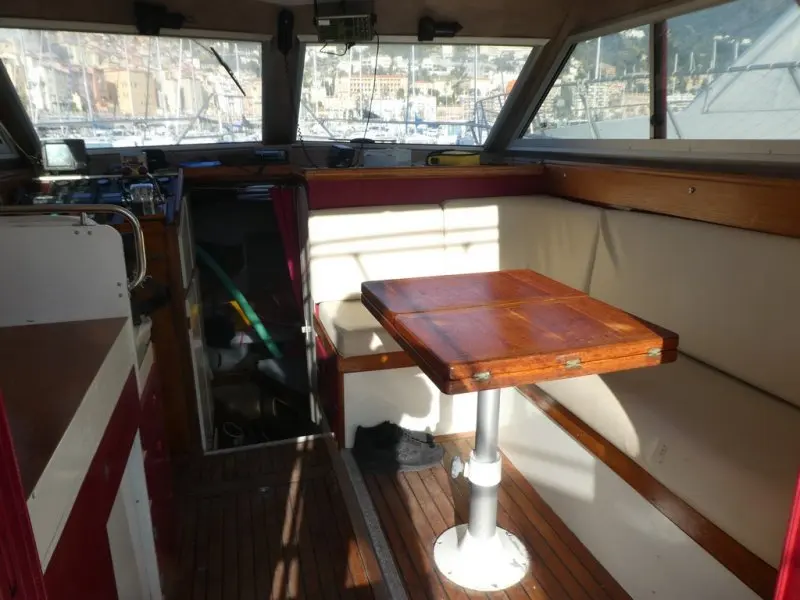 Arcoa 1080 Fishing — Vue du carré intérieur avec banquette, table et poste de pilotage.