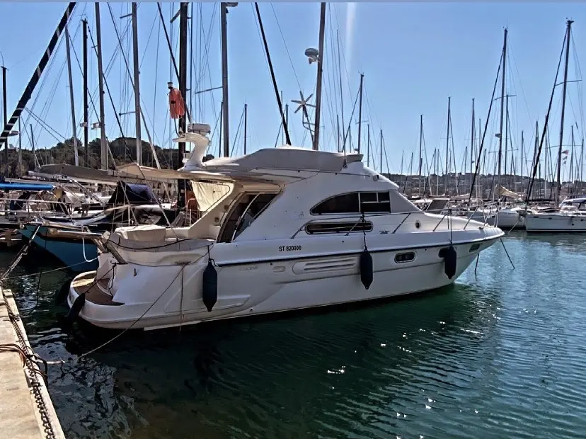 Sealine 350 Fly — Bateau à moteur blanc amarré dans un port de plaisance, vu de trois quarts arrière.