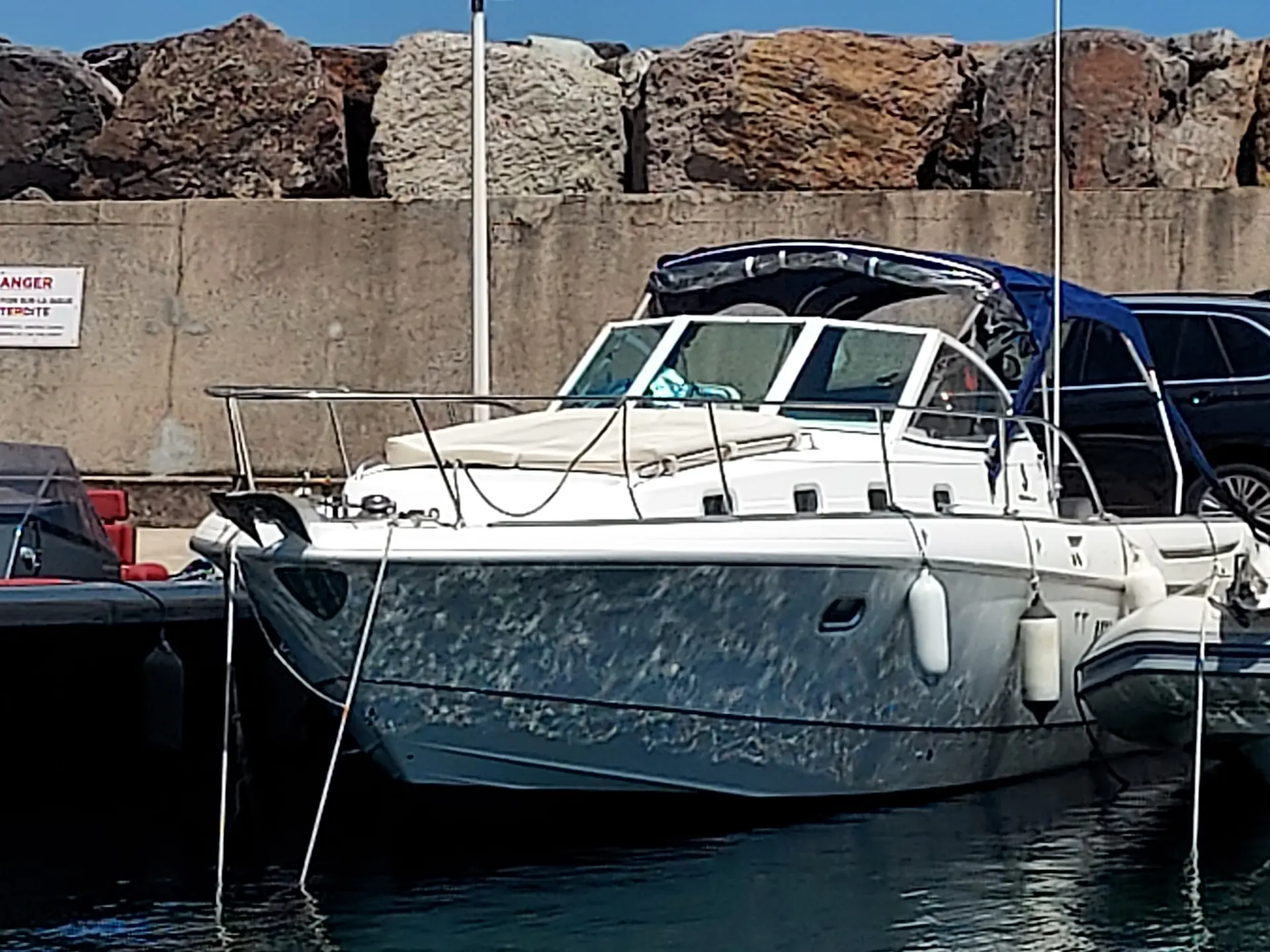 Beneteau Ombrine 1001 — Bateau à moteur blanc amarré dans un port, vu de trois quarts avant.