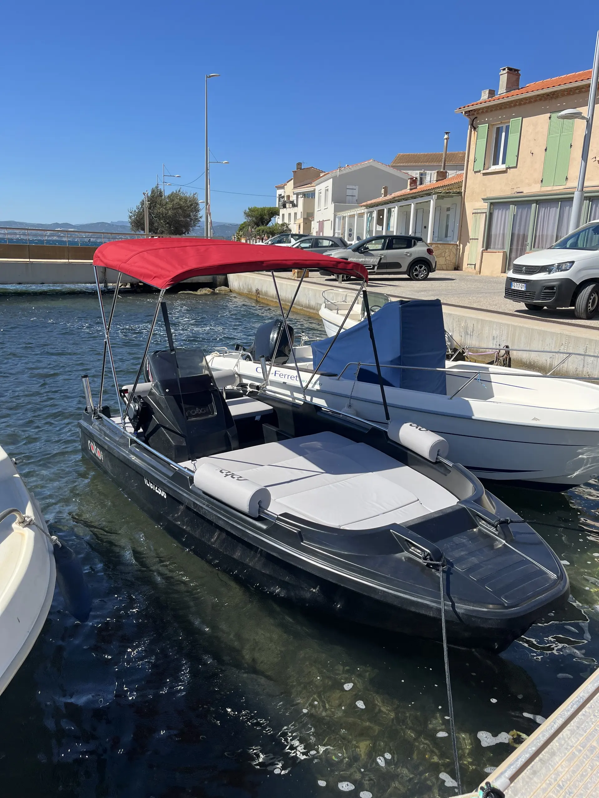 Roto 450 S Family — Bateau à moteur amarré dans un port, vu de trois quarts sous une bâche rouge.
