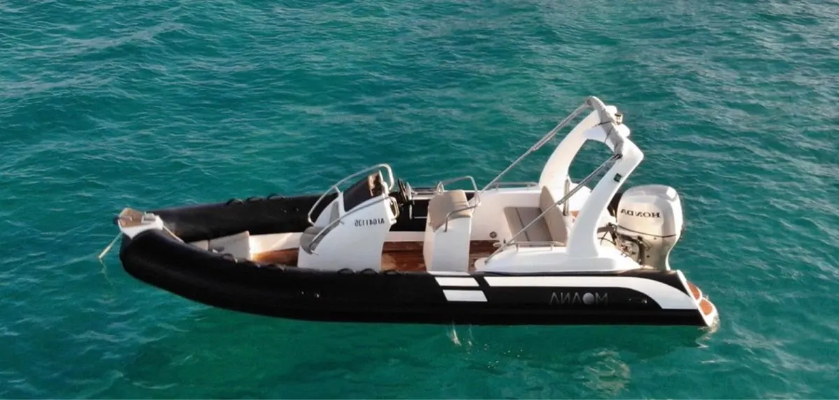 Moana 580 — Bateau semi-rigide noir et blanc vu de profil sur une mer turquoise.