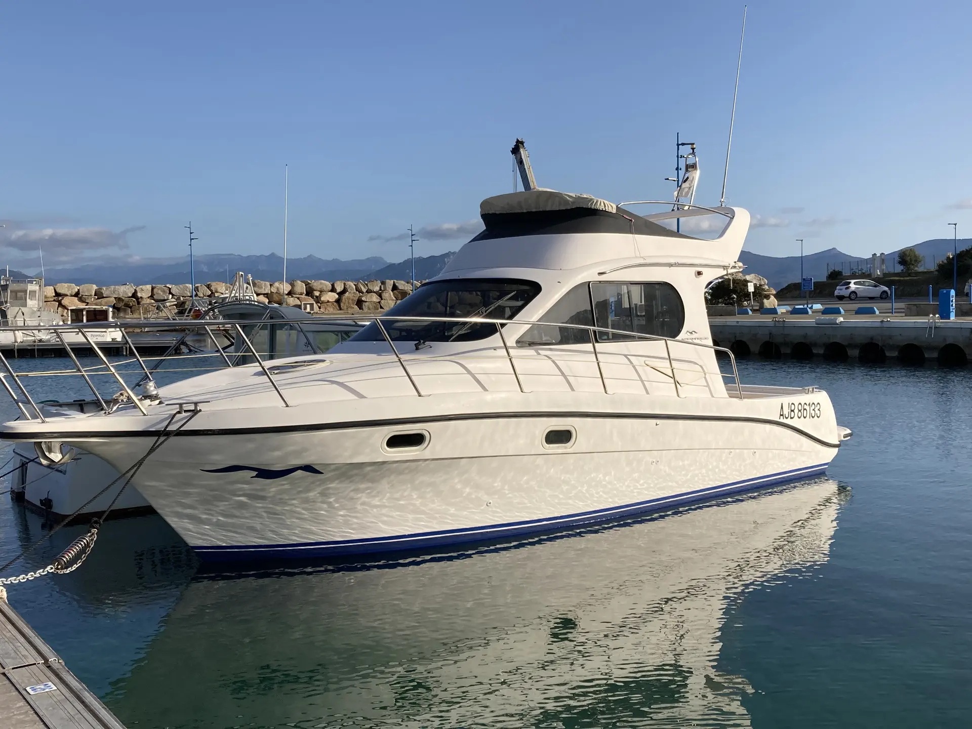 Intermare 30 Fly — Bateau à moteur blanc vu de trois quarts dans un port, sous un ciel dégagé.