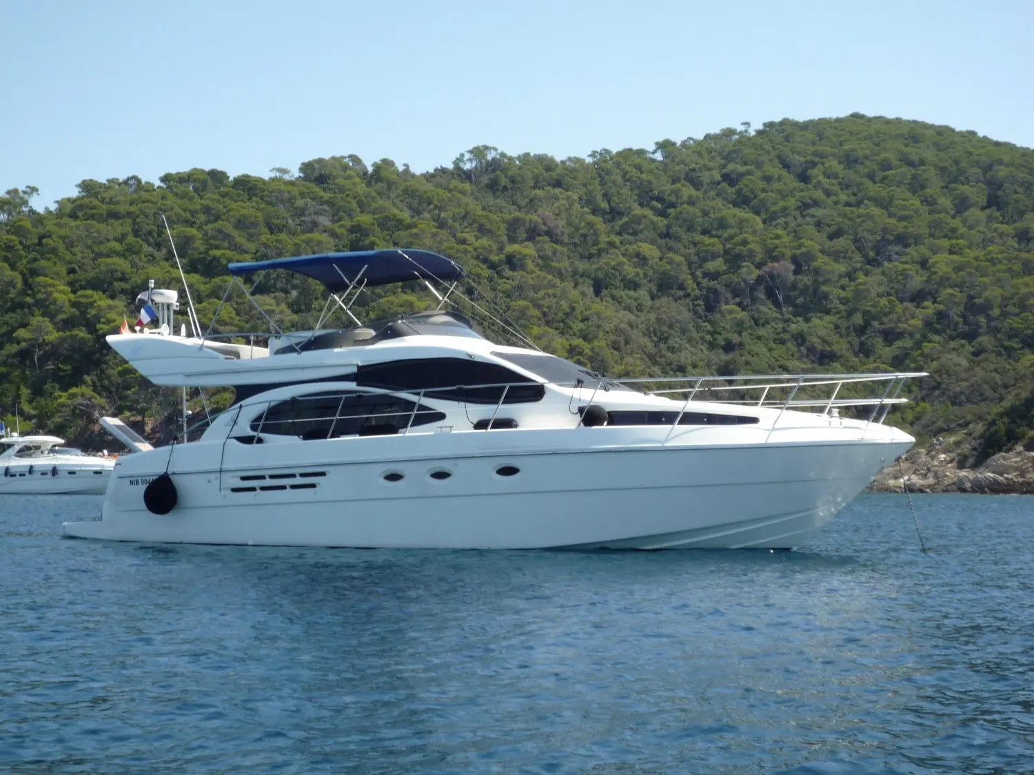 Azimut 46 — Bateau à moteur blanc photographié de profil dans une baie boisée.