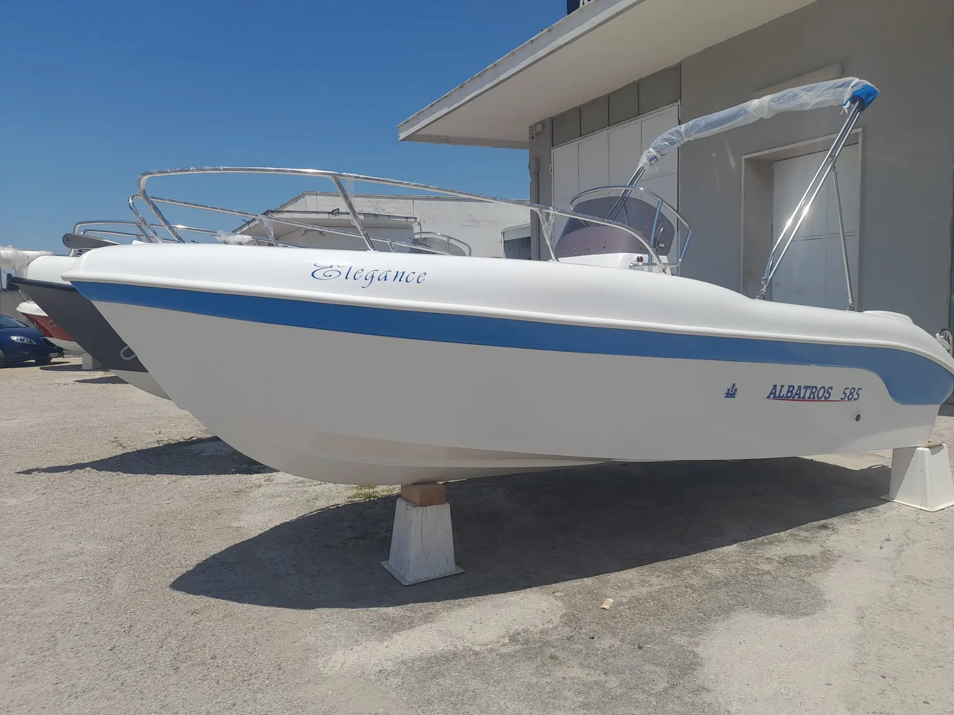 Albatros 585 — Bateau blanc et bleu présenté à terre, vu de profil devant un bâtiment.