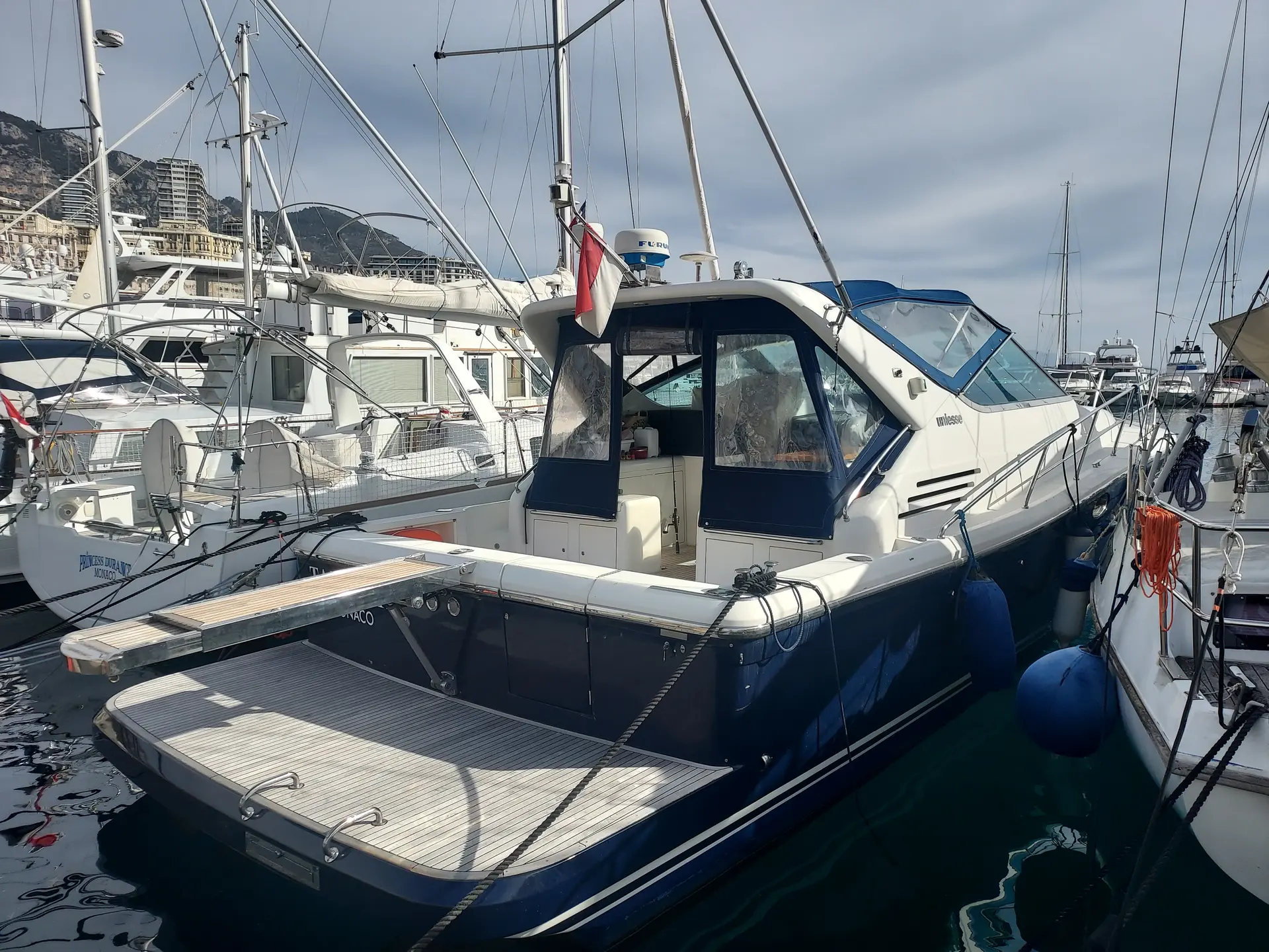 Uniesse 42 Open — Bateau à moteur amarré dans un port, vu de trois quarts arrière.