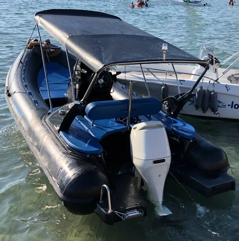 Master Summer — Bateau pneumatique à coque rigide vu de l’arrière, avec taud et moteur hors-bord.