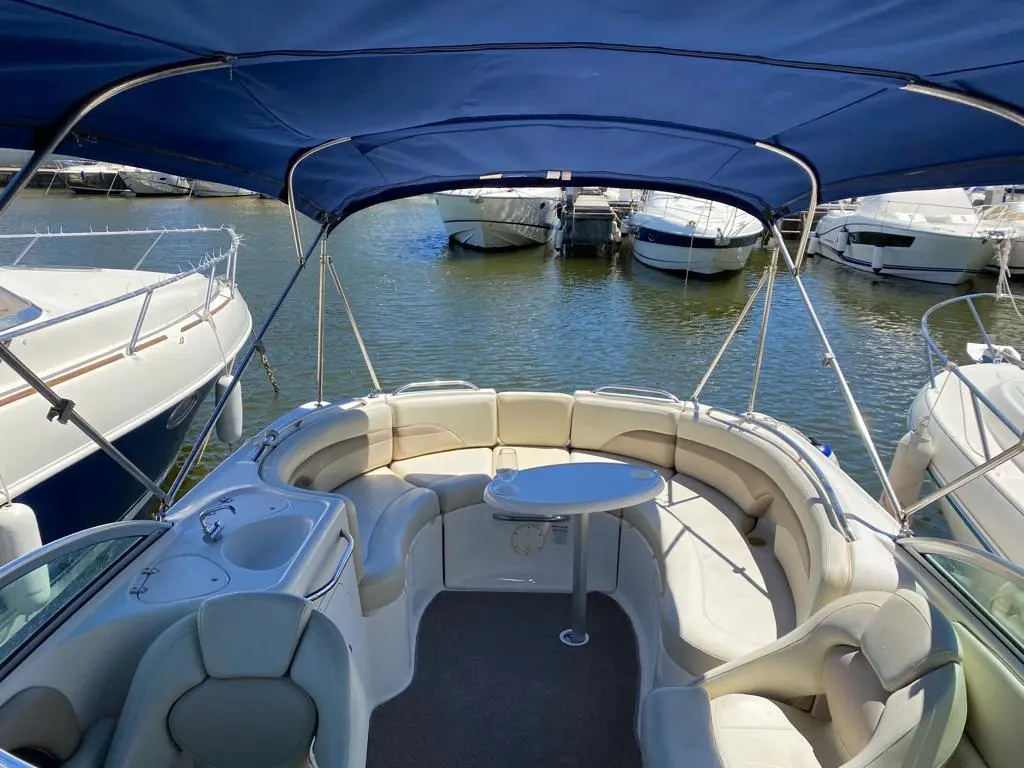 Chaparral Sunesta 274 — Cockpit avant d’un bateau de plaisance avec banquette circulaire et taud bleu.
