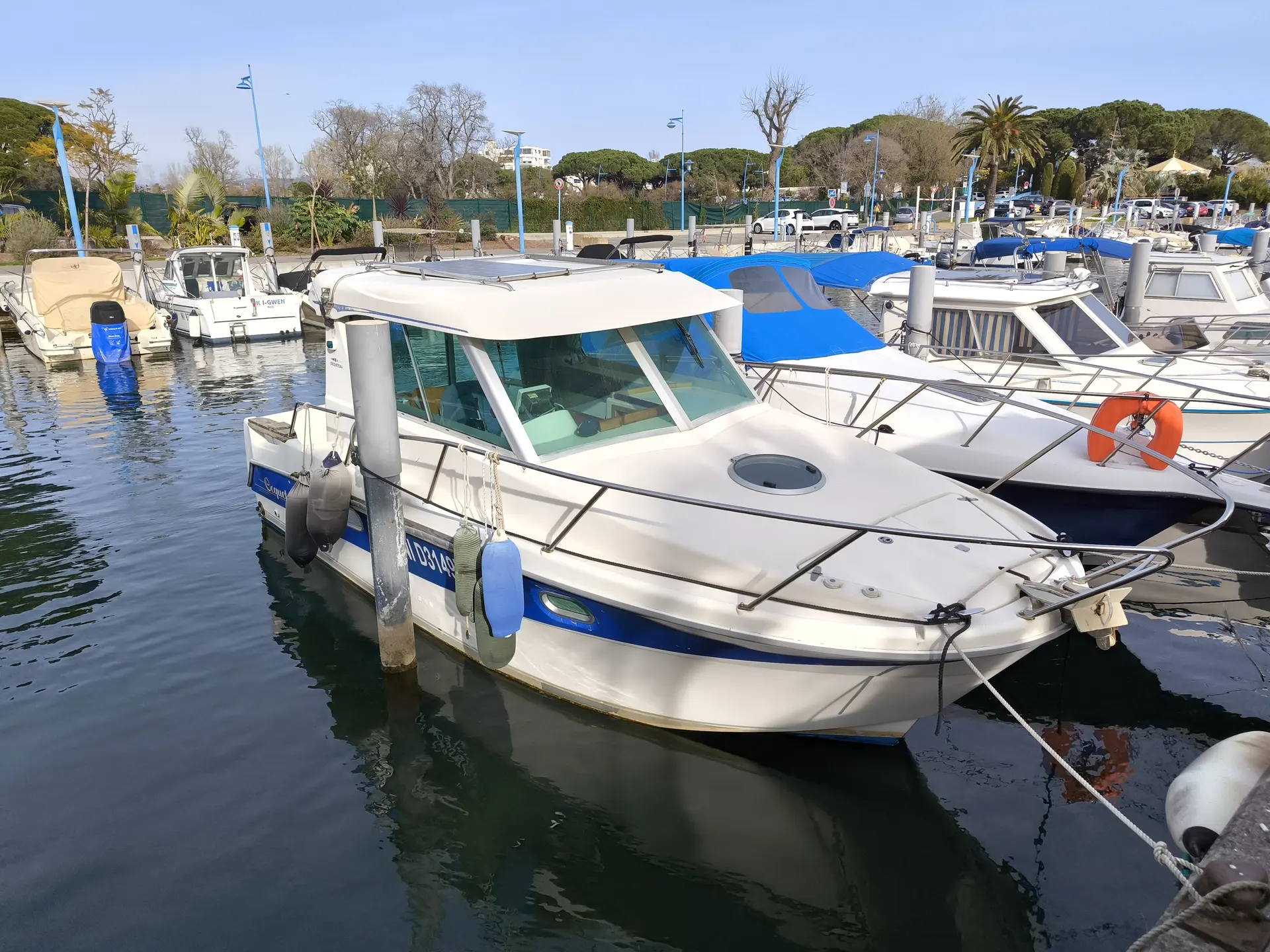 Ocqueteau 815 — Bateau à cabine blanche et bleue amarré dans un port de plaisance.