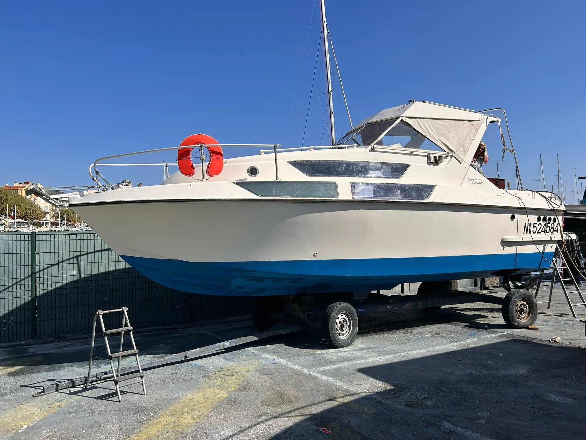 Coronet 26 Family — Bateau à moteur blanc et bleu posé sur sa remorque dans une marina.