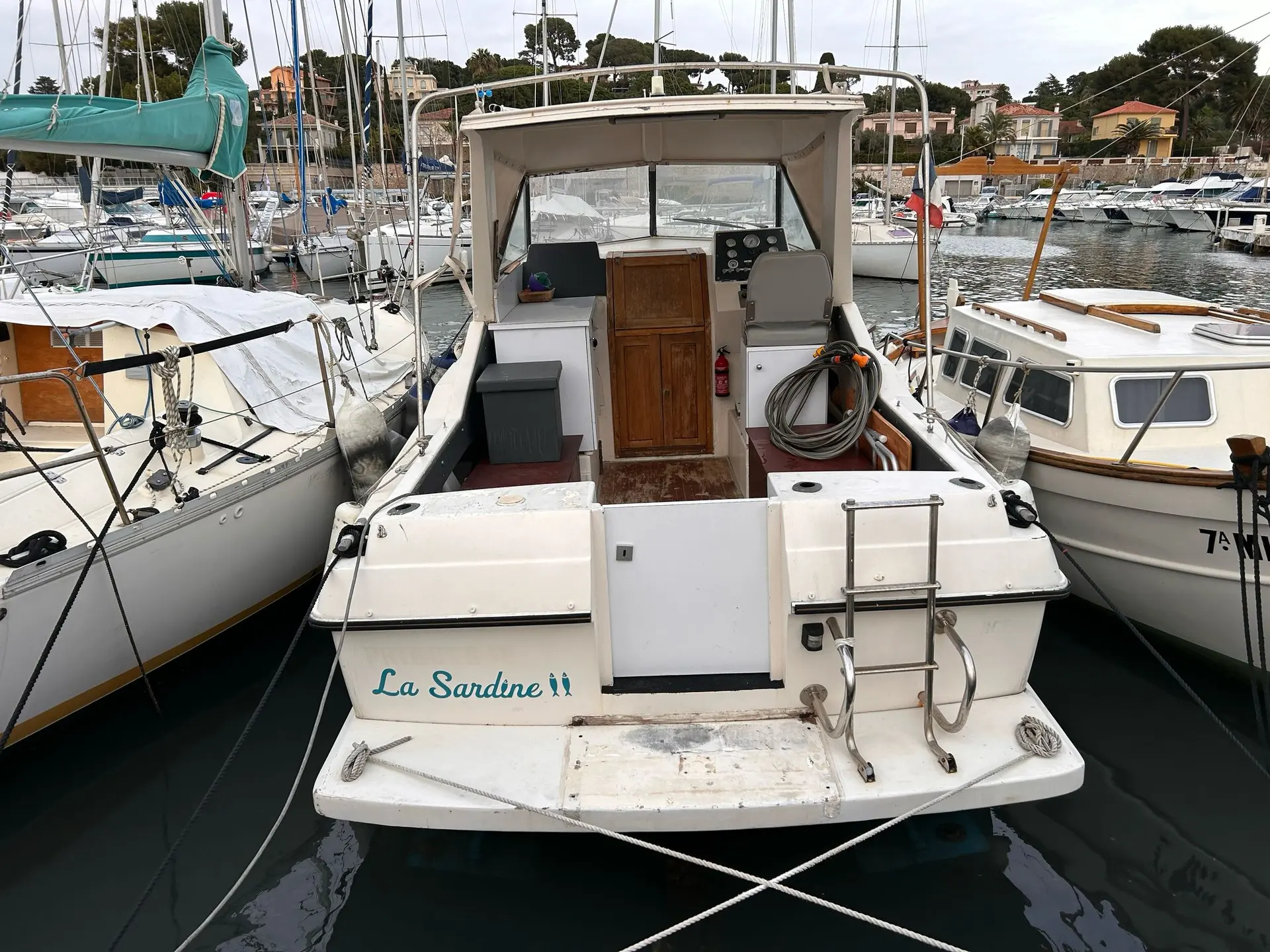 Coronet 26 Family — Vue arrière d’un bateau blanc amarré dans une marina, avec cockpit et cabine visibles.