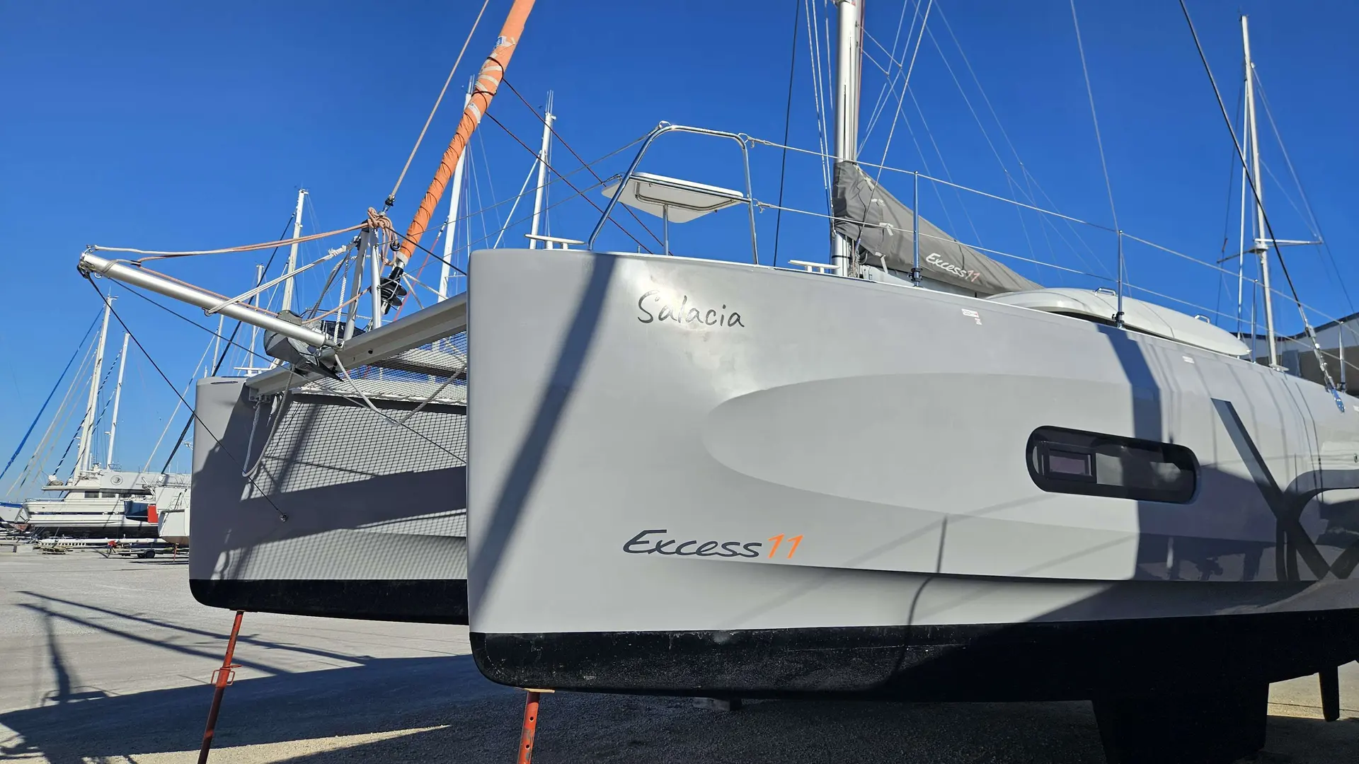 Beneteau Excess 11 — Vue rapprochée de la coque tribord d’un catamaran blanc à quai.