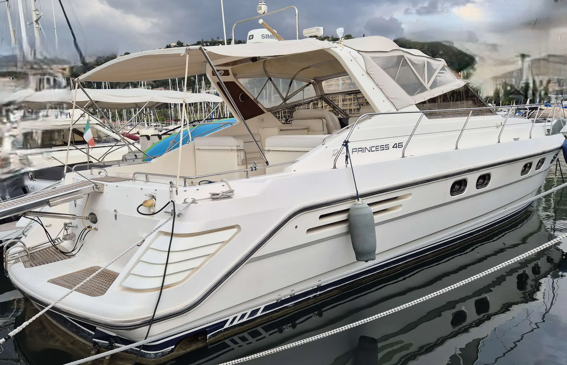 Princess Riviera 46 — Bateau à moteur blanc amarré dans une marina, vu de trois quarts arrière.