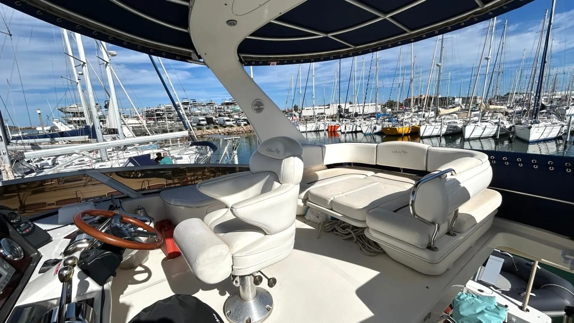 Sea Ray 455 Sundancer — Vue du poste de pilotage et du cockpit d’un bateau amarré dans une marina.