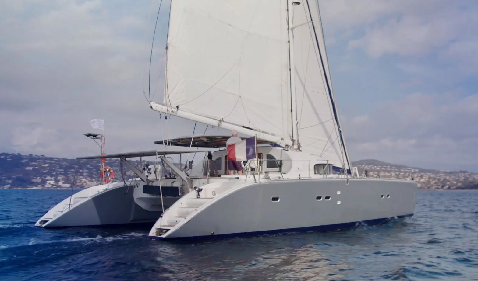 Cnb LAGOON 570 — Catamaran à voile naviguant au large, avec une personne visible sur le pont.