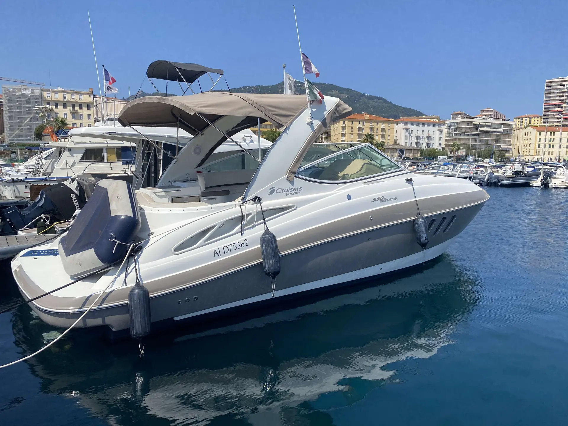 Cruisers Yachts 330 Express — Bateau à moteur blanc amarré dans un port, vu de trois quarts tribord.