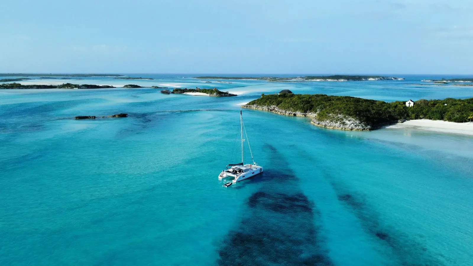 Outremer 45 — Catamaran blanc vu du ciel dans des eaux turquoise près d’îlots.