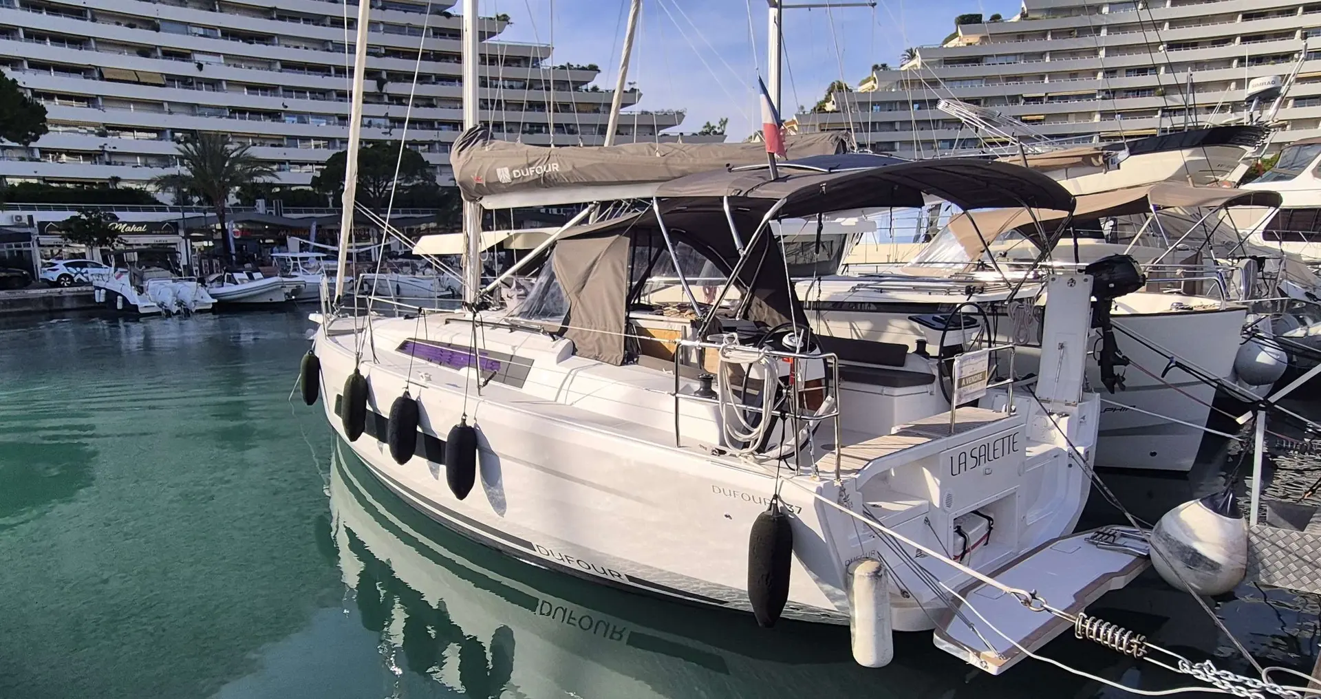 Dufour 37 — Voilier blanc amarré dans un port, vu de trois quarts arrière.