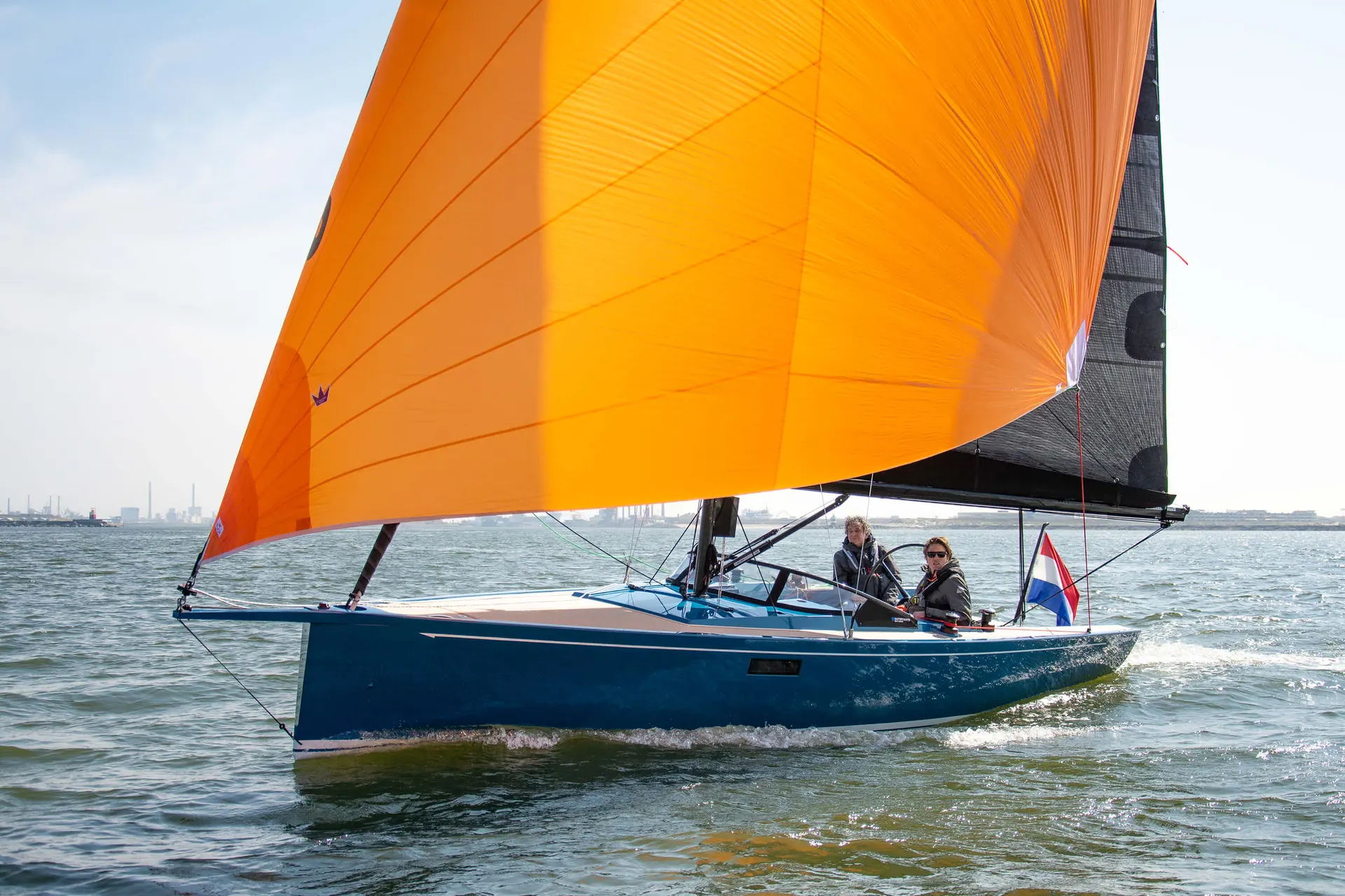 Saffier SE 27 Leisure — Voilier bleu naviguant sous voile orange, avec deux personnes à bord.