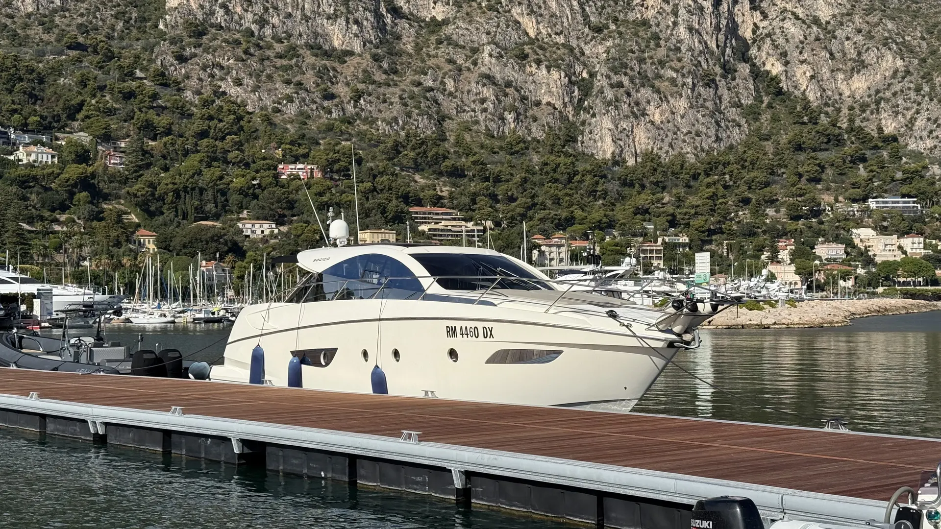 Sogica 47 Openbridge — Bateau à moteur amarré dans un port, devant une côte rocheuse.