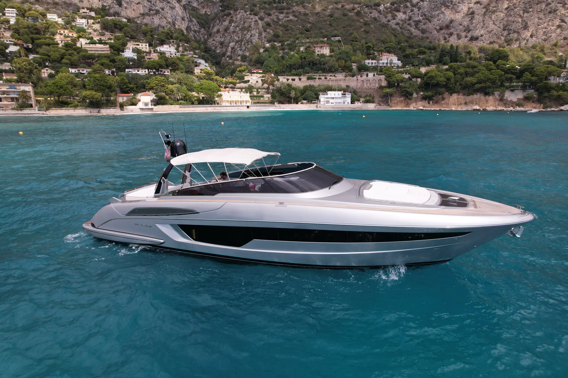 Riva Rivale 56 — Vue latérale d’un bateau à moteur naviguant devant une côte méditerranéenne.