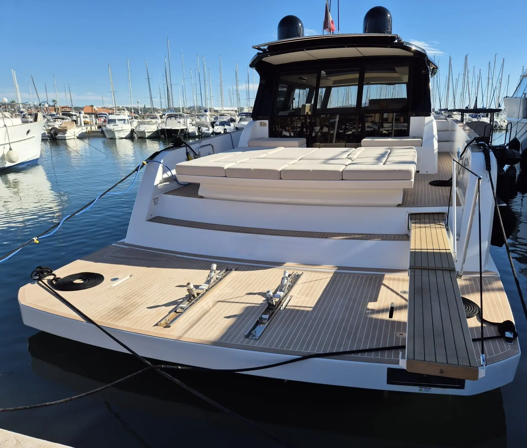 Pardo Yachts Pardo 52 GT — Vue arrière d’un yacht amarré, avec vaste plage arrière et salon fermé.