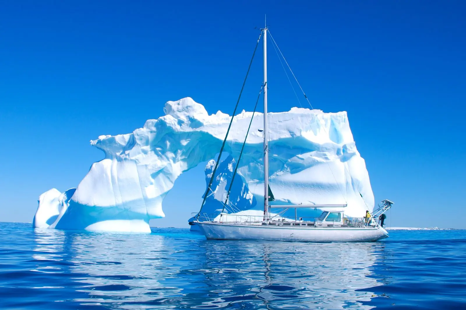 CNM Via 52 — Voilier vu de profil devant un iceberg, en mer sous un ciel dégagé.