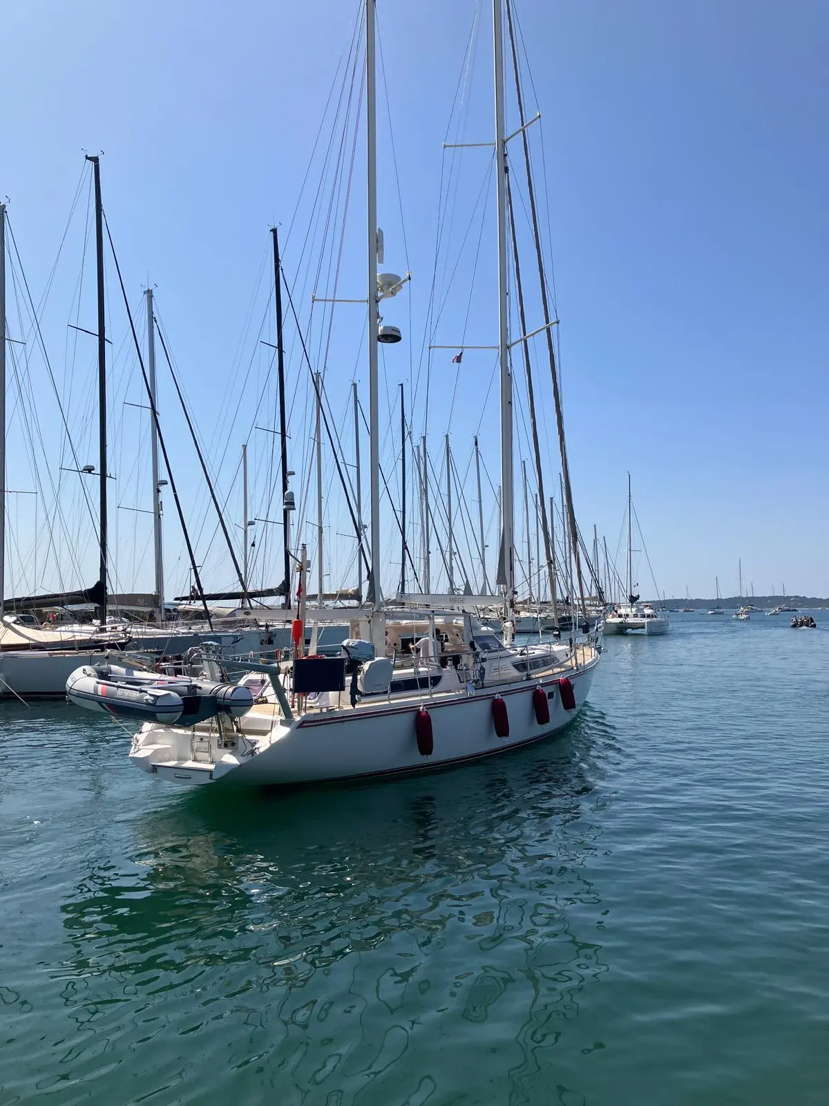 Amel 54 — Voilier blanc amarré dans une marina, entouré d'autres bateaux.