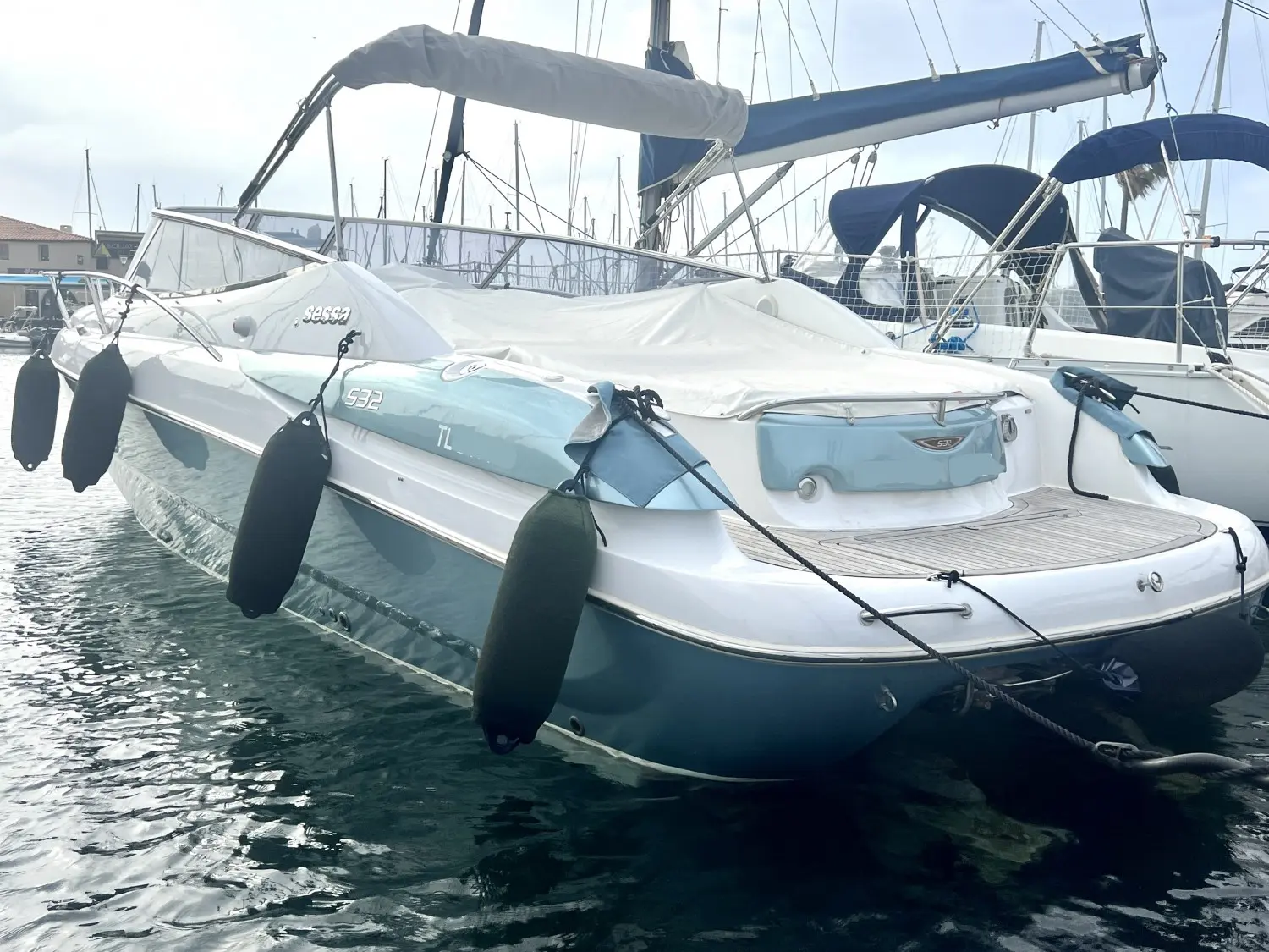 Sessa Marine S32 — Bateau à moteur blanc et bleu amarré dans un port, vu de trois quarts arrière.