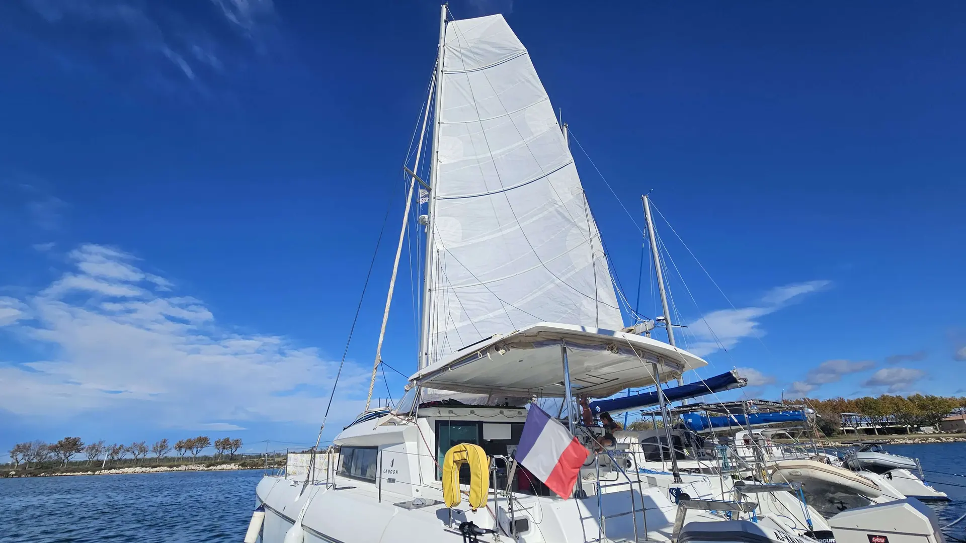 Lagoon 420 — Catamaran à voiles blanc amarré dans un port sous un ciel dégagé.