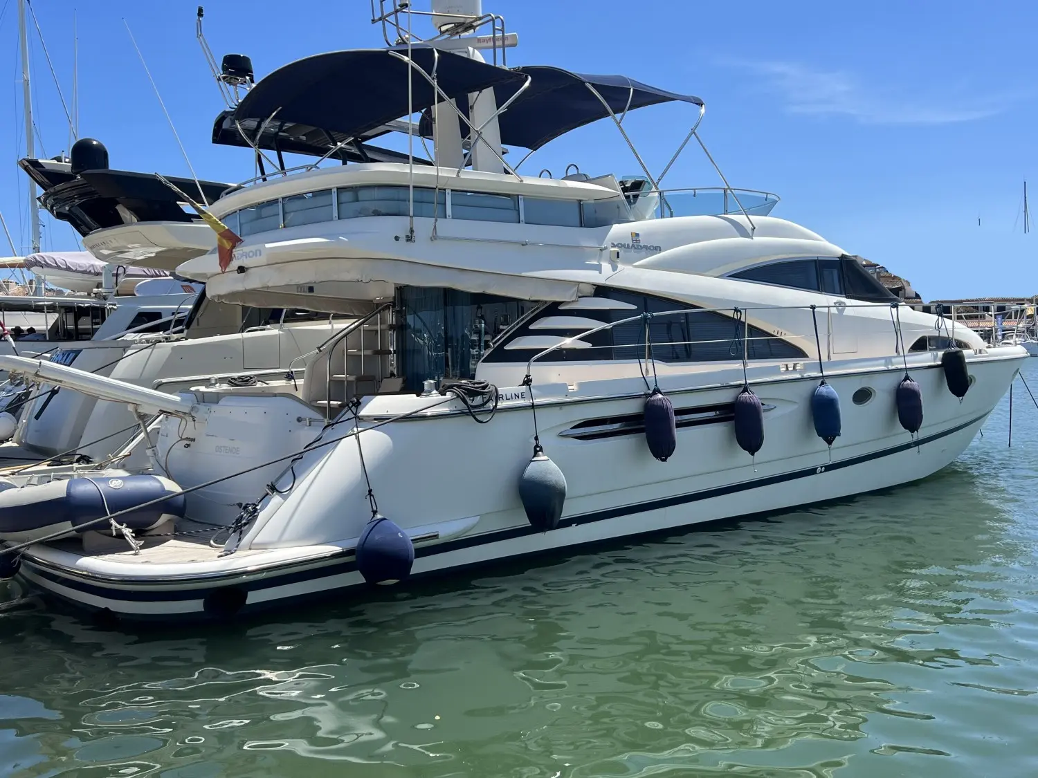 Fairline Squadron 58 — Bateau à moteur blanc amarré dans une marina, vu de trois quarts arrière.